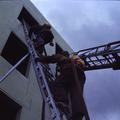 Two firemen climbing a ladder into a building