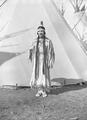 Young Native American woman standing next to tepee