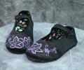Child's Mary-Jane style slippers of black satin with dark lavender floral embroidery in satin stitch at the toe area