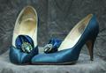 Pumps of cerulean blue silk satin with self-satin fan-like accent on vamp that is embellished with a rhinestone jewel