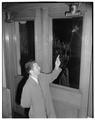 Examining a broken glass door, 1954