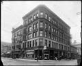 Woodard Clark & Co. drug store at corner of 7th and Washington, Portland. Power lines over street in foreground.