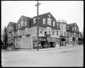 New Castle Apartments at 3rd and Harrison, Portland. Ogden Grocery and Deli at street level. Two people in upper window. Van Camp Pork and Beans Advertisement in store window.