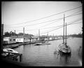 Row of boat houses at Oregon Yacht Club, Portland. Three sailboats in foreground, power lines overhead.