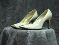 Pumps of off-white leather with pointed toe tipped in gold metal