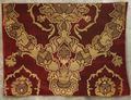 Textile panel of deep red velvet with a voided design in gold metallic