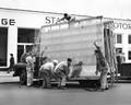 Men lifting glass off truck to put in Stan Baker Motors window