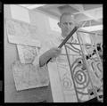 An unidentified faculty member posing with topographic maps