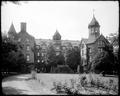 Building and grounds of St. Helens Hall, Portland. Building hidden behind tree along Montgomery St. in foreground.