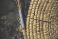 Round mat in progress, detail of needles and binding needle, shows drinking straw used to hold needles