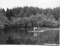 People on raft and man in boat on river