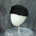 Toque style hat of black silk velvet with pinwheel pleating at center of crown
