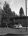 View of portion of building, truck and man. Trees in background. See 02-137