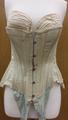 Corset of ivory cotton with hook closings at front and lace closings at back