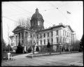 Full view of State Capitol, Salem. Sidewalk leading up to front steps. Street in foreground with streetcar tracks and power lines. Trees along street.