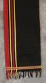 Shawl of hand-woven black, red, and yellow cotton trimmed at the ends in loop stitched stripes in white, green, fuchsia, red, and yellow