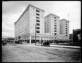 Hotel Multnomah from corner of Pine and 4th, Portland. Autos on street, vacant lot in foreground. Flags and bunting on building. Coca Cola advertisement in the lower left corner