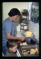 Child with person churning butter, Oregon, circa 1971