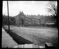 Full view of Portland Academy, surrounded by iron fence. Wooden sidewalk along 13th St. in foreground.