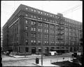 Weinhard Building, with Wadhams & Co. Grocer and Goodyear Rubber Co., at 4th and Oak, Portland. Men standing on corner, horse-drawn wagon at base of building.