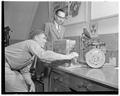 R. W. Peterson, graduate assistant, and Milosh Popovich, staff member, around equipment that tested engine wear in automobiles with radioactive pistons, 1953