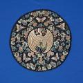 Textile roundel of black silk satin richly embroidered with crane in center