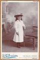 Young girl wearing white dress and hat with flowers