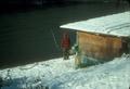 Man fishing along bank of river