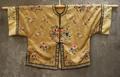 Short jacket of tan silk damask patterned with floral motif and swastika
