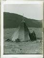 Woman standing next to tepee (along Columbia River?)