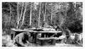 Four men building log table and benches