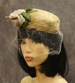 Pillbox hat of ecru feathers with fabric corsage at front