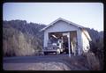 Truck passing through Upper Grave Creek covered bridge, Oregon, 1967