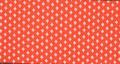 Textile sample of red polyester knit with pattern of tiny white spades