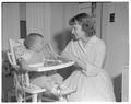 A Home Economics student feeding a "practice baby" in the Kent House, May 1958