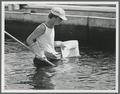 Student with fish net in waist-deep water