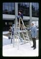 Nancy Marqueling, Kay Conrad, and Dan Poling posing with ladders and temporary fencing in front of Administration Building, Oregon State University, Corvallis, Oregon, circa 1972