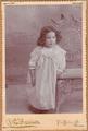 Little girl with dark curly hair wearing a silky gown with lace around the bodice