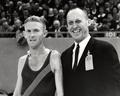 Bill Bowerman and a runner at an indoor meet