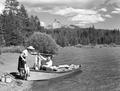 Man and woman with boat on shore holding caught fish