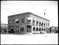 Benton County National Bank, Corvallis, on street corner, surrounded by small shops. Horse and buggy parked by building.