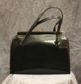Handbag of black patent leather with patent leather covered frame with accents and clasp of gold metal