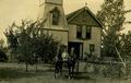 Man in a horse drawn carriage with house in background