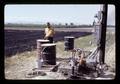 Art King in field with barrels, Halsey, Oregon, circa 1971