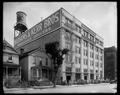 Wadhams & Kerr Bros. Wholesale Grocers on Hoyt at 4th, Portland. Groceries on carts along street, houses next to building, water tank on roof.