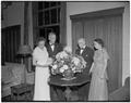 President Strand and Chancellor Byrne examining a floral arrangement with their wives at the president's reception, held in the Memorial Union