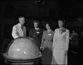 President Strand and guests at a Summer Session reception gathered near an oversized globe, Memorial Union
