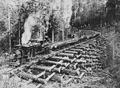 Locomotive pulling railroad cars with logs over a crib trestle