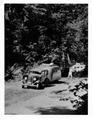 Car with camping trailer on parking strip. One shot shows man walking.