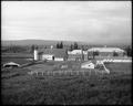 General view of buildings and grounds, Multnomah County Poor Farm. Fields and pens in foreground, large barn and dorm building in background.